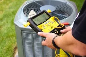 Person using a yellow digital gauge to check or service an outdoor air conditioning unit.